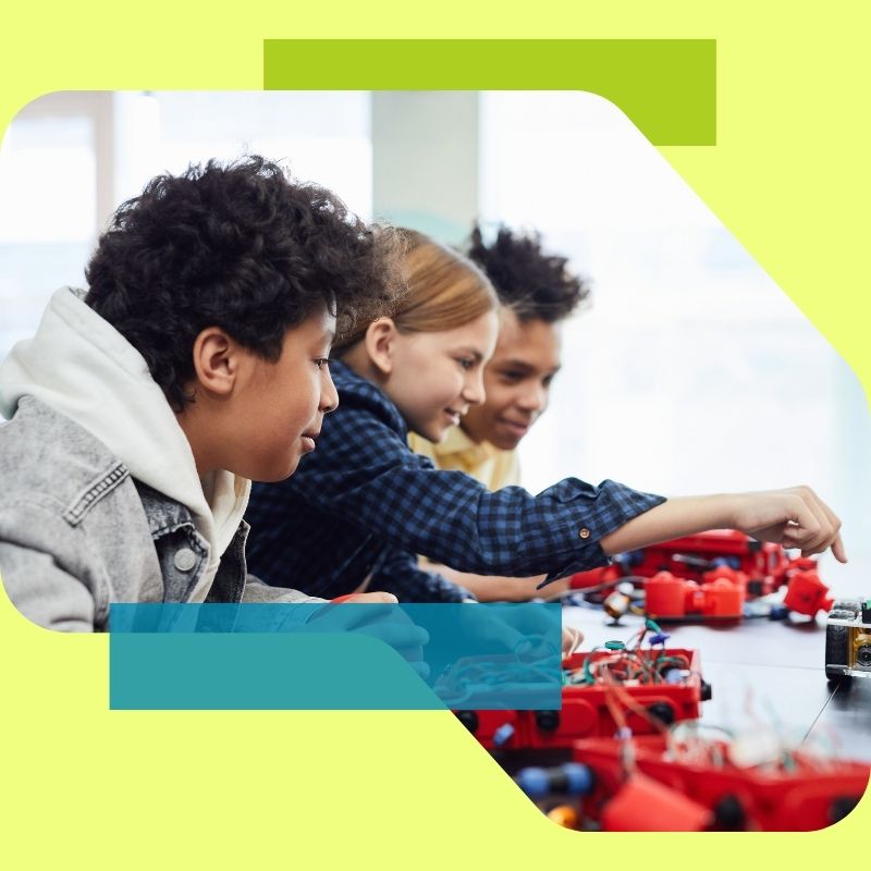 Drei Kinder, die an einem Tisch sitzen und motiviert an einem Projekt arbeiten